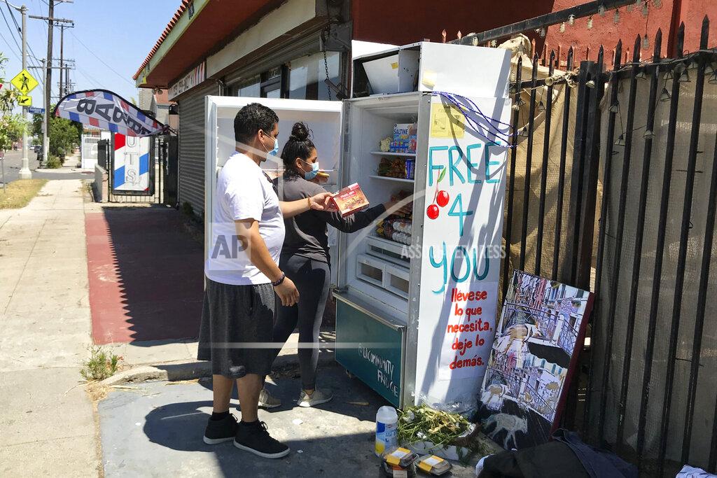 Aron Ranen Volunteers Bryant Rodriguez and his daughter Vanessa Rodriguez stock a refrigerator with free food for people in need in Los Angeles on July 20, 2020. A network called, LA Community Fridge, has placed a number of them across the Los Angeles area, from the Highland Park neighborhood north of downtown to Exposition Park near the University of Southern California to the seaside city of Long Beach, with plans to install more. (AP Photo/Aron Ranen)