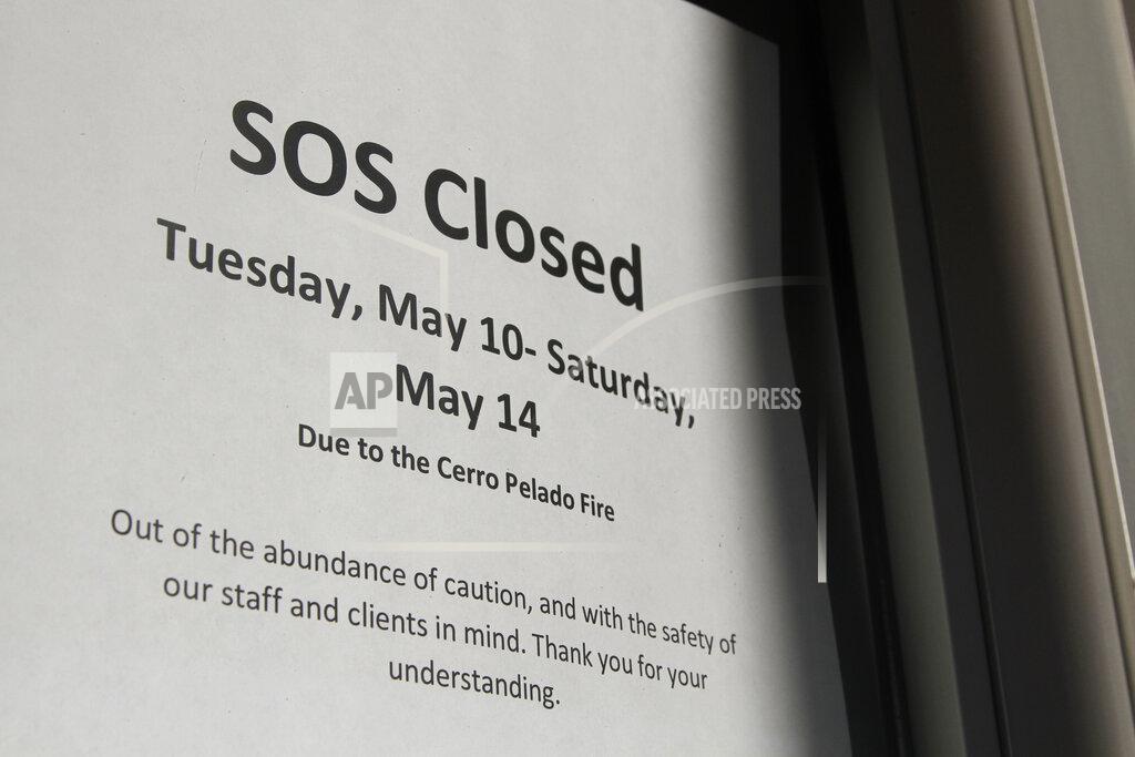 Morgan Lee A storefront window announces a weeklong work hiatus on Thursday, May 12, 2022, as residents of Los Alamos, N.M., prepared to possibly flee a wildfire as it crept within a few miles of the city and companion national security laboratory. Scientists at Los Alamos National Laboratory are using supercomputers and ingenuity to improve wildfire forecasting and forest management amid drought and climate change in the American West. (AP Photo/Morgan Lee)