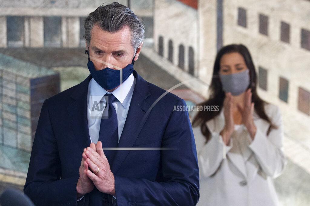 Jessica Christian Gov. Gavin Newsom is applauded by Oakland Mayor Libby Schaaf as he takes the stage during a news conference held at Unity Council career center in the Fruitvale neighborhood of Oakland, Calif., on Monday, May 10, 2021. (Jessica Christian/San Francisco Chronicle via AP)