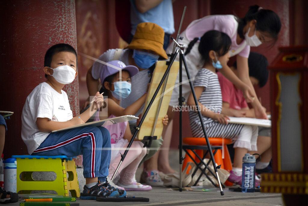 Mark Schiefelbein Children wearing face masks to protect against the coronavirus sketch the Temple of Heaven in Beijing, Saturday, July 18, 2020. Authorities in a city in far western China have reduced subways, buses and taxis and closed off some residential communities amid a new coronavirus outbreak, according to Chinese media reports. They also placed restrictions on people leaving the city, including a suspension of subway service to the airport. (AP Photo/Mark Schiefelbein)