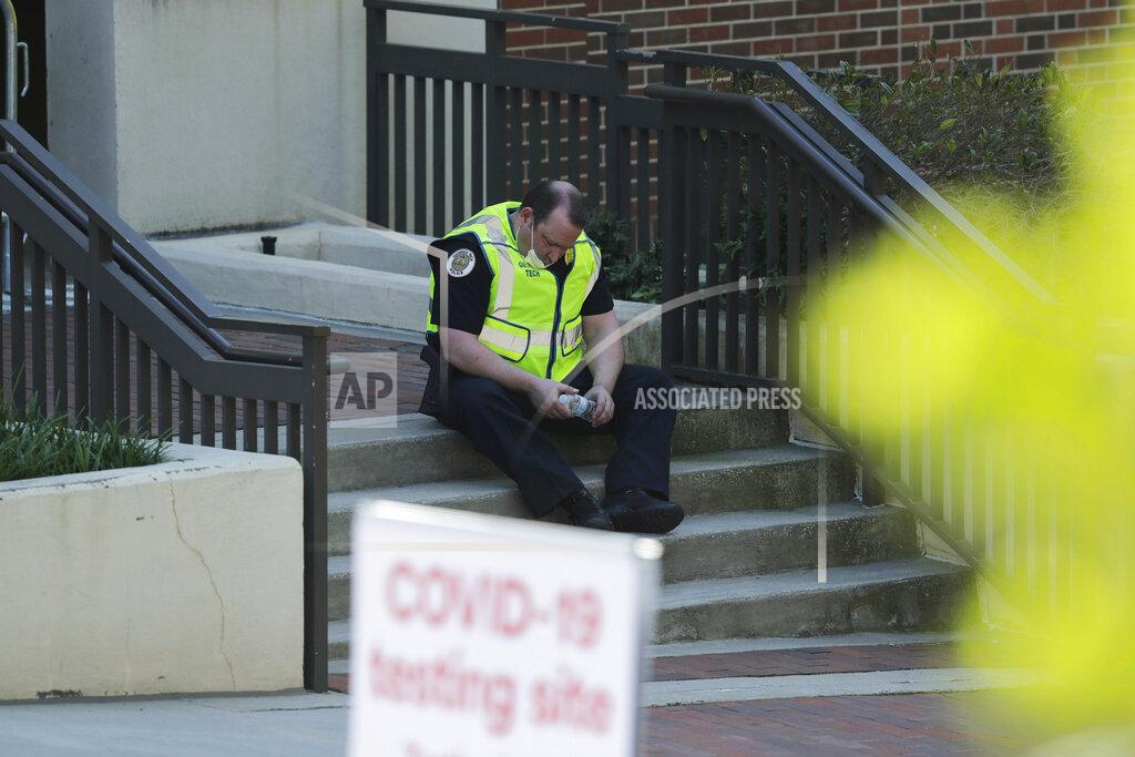 Brynn Anderson An official rests on a stoop near a COVID-19 testing site on Georgia Tech's campus, Monday, April 6, 2020, in Atlanta. (AP Photo/Brynn Anderson)
