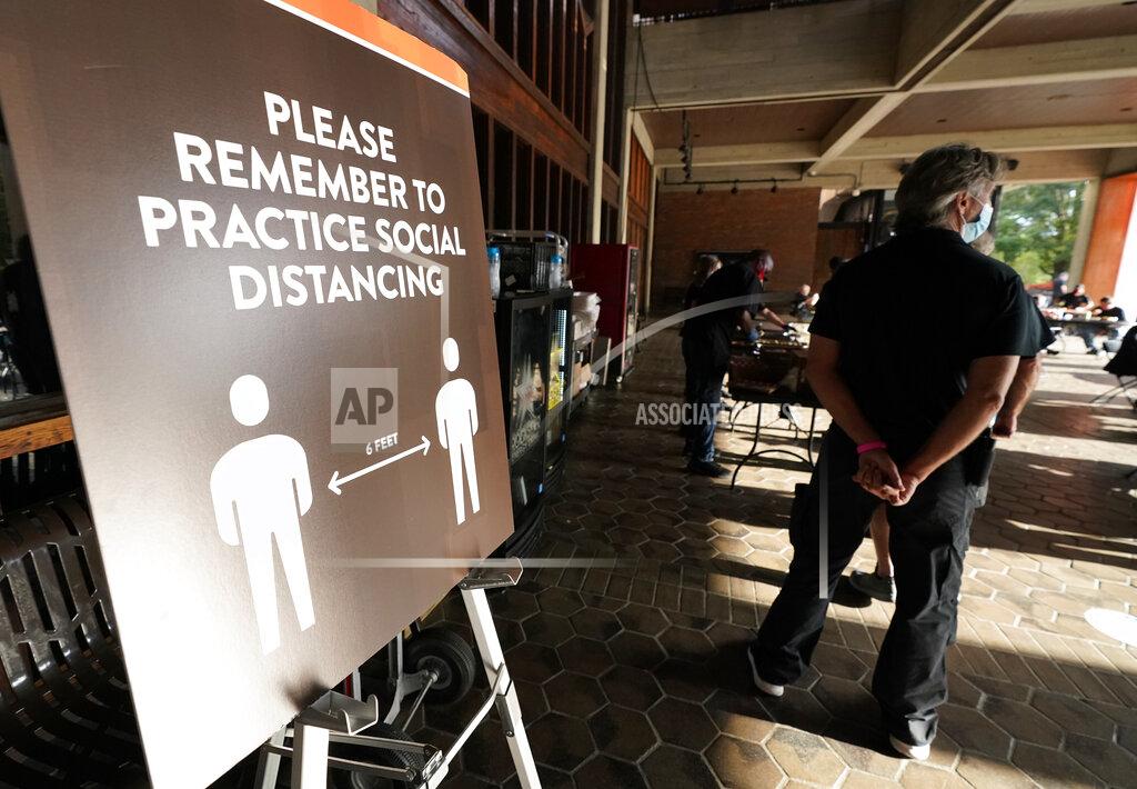 Mark Humphrey Event staff stand at the entrance to the Grand Ole Opry House near signs encouraging social distancing during the 55th annual Academy of Country Music Awards on Wednesday, Sept. 16, 2020, in Nashville, Tenn. (AP Photo/Mark Humphrey)