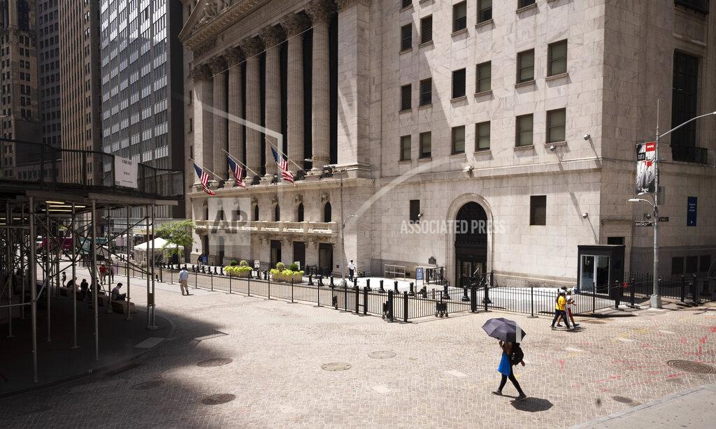 FILE - People pass the New York Stock Exchange, Thursday, July 30, 2020. Wall Street is stalling on Friday, Aug. 7 as a whirlwind of worries about rising U.S-China tensions and whether Congress can deliver more aid for the economy threaten to halt its big run.(AP Photo/Mark Lennihan)