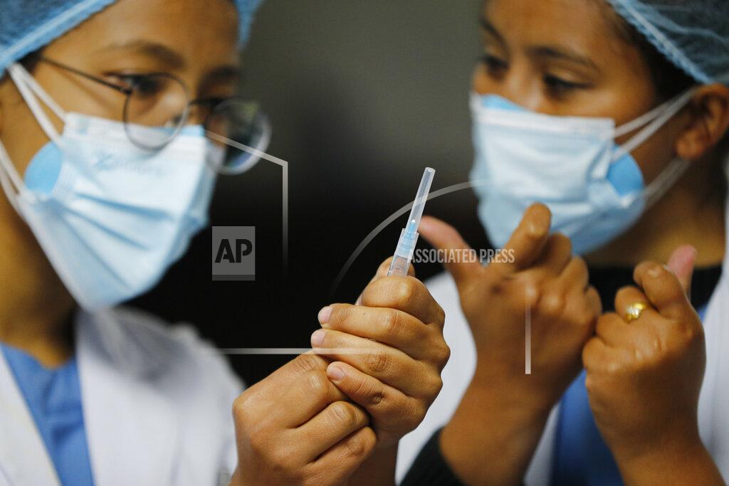Niranjan Shrestha A Nepalese health worker, right, instructs another on administering COVID-19 vaccine at Teaching Hospital in Kathmandu, Nepal, Wednesday, Jan. 27, 2021. Thousands of health workers lined up across Nepal to get the coronavirus vaccine Wednesday as the Himalayan nation began its campaign to get the population vaccinated within three months. Neighboring India gifted Nepal 1 million doses of the AstraZeneca-Oxford University vaccine manufactured under license by the Serum Institute of India. (AP Photo/Niranjan Shrestha)