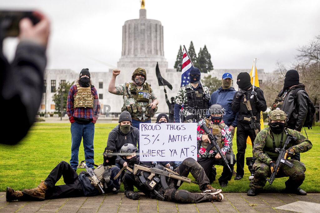 Noah Berger Armed protesters, who identified themselves as Liberty Boys, pose for fellow demonstrators' pictures outside the Oregon State Capitol on Sunday, Jan. 17, 2021, in Salem, Ore. The group said they want reduced government and do not support President Donald Trump or President-elect Joe Biden. (AP Photo/Noah Berger)