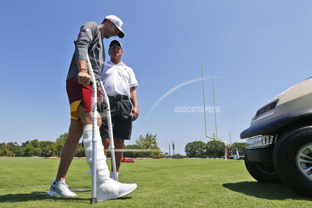 Steve Helber FILE - In this July 25, 2019, file photo, injured Washington Redskins quarterback Alex Smith, left, walks to a cart as he talks with former quarterback Joe Theisman, right, as he leaves the practice field during the first day of NFL football training camp in Richmond, Va. Alex Smith is not only active and back on the practice field but actually taking some second-team snaps in team drills at Washington's training camp 21 months after breaking his right tibia and fibula, a gruesome injury that required multiple surgeries and threatened his career. Now the veteran quarterback seems close to completing an improbable comeback. (AP Photo/Steve Helber, File)