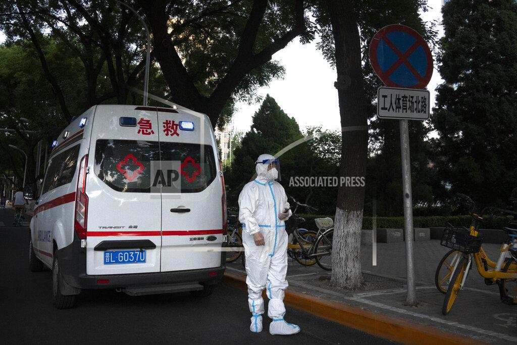 Mark Schiefelbein A worker wearing a protective suit to help protect against COVID-19 stands outside an ambulance parked along a street in Beijing, Thursday, May 26, 2022. (AP Photo/Mark Schiefelbein)