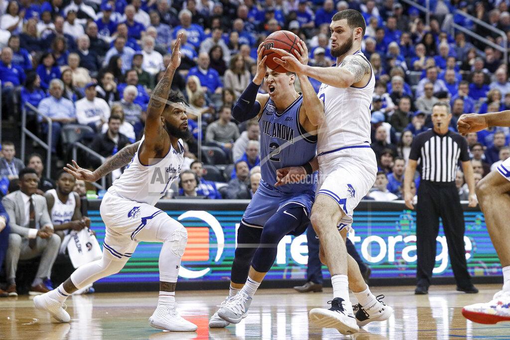 John Minchillo Villanova's Collin Gillespie (2) drives against Seton Hall's Sandro Mamukelashvili, right, and Seton Hall's Myles Powell, left, during the first half of an NCAA college basketball game, Wednesday, March 4, 2020, in Newark, N.J. (AP Photo/John Minchillo)
