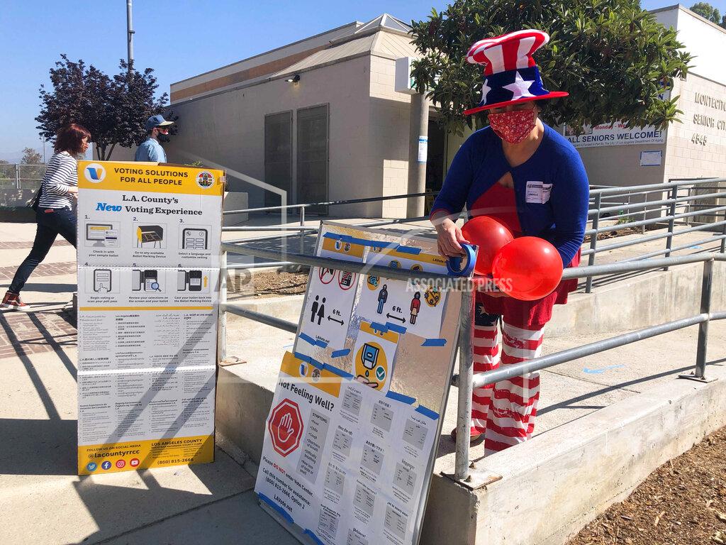 Stefanie Dazio Camille Teran-Grange, a volunteer at polling place at the Montecito Heights Senior Citizen Center in Los Angeles, adds balloons to voter information placards on Tuesday, Sept. 14, 2021. (AP Photo/Stefanie Dazio)
