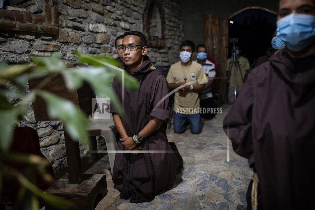 Rodrigo Abd Seminarist Oveniel Garcia, 21, left, kneels during a Mass celebrated by Friar Leopoldo Serrano in the chapel at Mission San Francisco de Asis, Honduras, Saturday, June 19, 2021. Garcia, a former drug addict and trafficker, entered the rehab center at the mission run by Serrano. Over the years, he became Serrano’s right-hand man. (AP Photo/Rodrigo Abd)