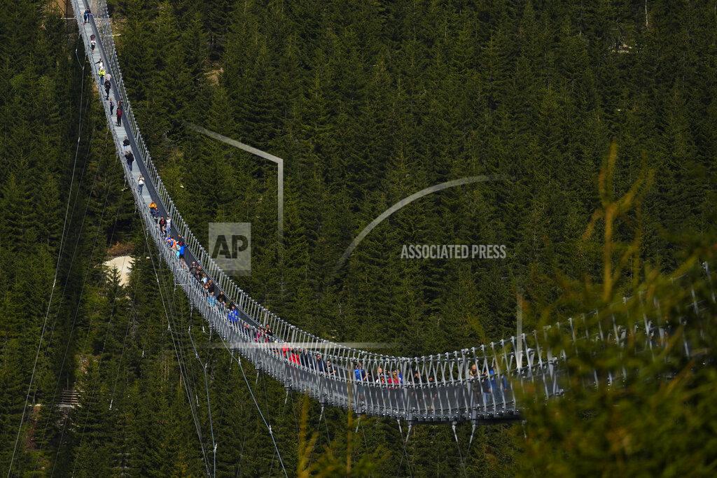 Petr David Josek Visitors cross a suspension bridge for the pedestrians that is the longest such construction in the world shortly after its official opening at a mountain resort in Dolni Morava, Czech Republic, Friday, May 13, 2022. The 721-meter (2,365 feet) long bridge is built at the altitude of more than 1,100 meters above the sea level. It connects two ridges of the mountains up to 95 meters above a valley between them. (AP Photo/Petr David Josek)