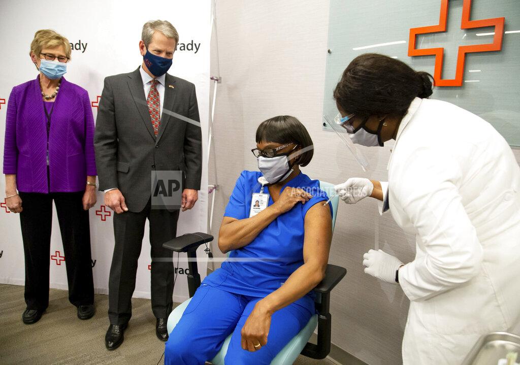 Steve Schaefer Georgia Gov. Brian Kemp, second from left, and Dr. Kathleen Toomey, left, look on as Grady ICU nurse Norma Poindexter receives her Pfizer-BioNTech COVID-19 vaccine at Grady Hospital, Thursday, Dec. 17, 2020, in Atlanta. (Steve Schaefer/Atlanta Journal-Constitution via AP)