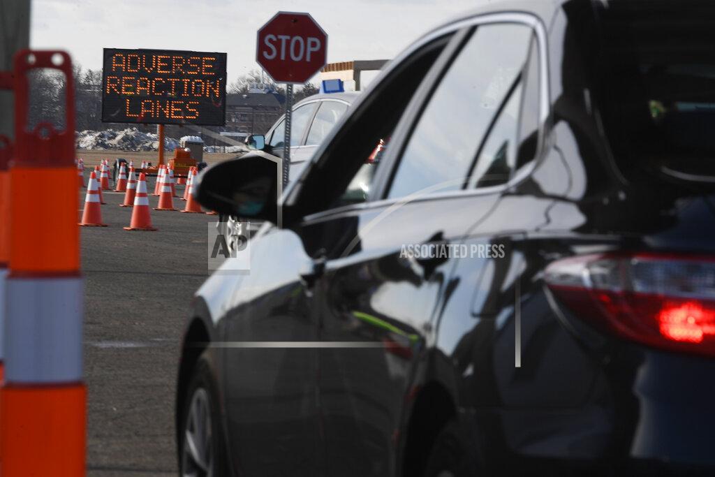 Jessica Hill A sign indicates where to drive if an adverse reaction to the vaccination occurs on opening day of the Connecticut's largest COVID-19 Vaccination Drive-Through Clinic Monday, Jan. 18, 2021, in East Hartford, Conn. The former Pratt & Whitney Runway has been converted into a ten-lane, drive-through COVID-19 Mass Vaccination Clinic, with the Pfizer-BioNTech vaccine being administered by Community Health Center, Inc. (CHC). Vaccinations are by appointment only to eligible individuals in Phase 1a and 1b through Connecticut's 211 system or the CDC's Vaccine Administration Management System. (AP Photo/Jessica Hill)