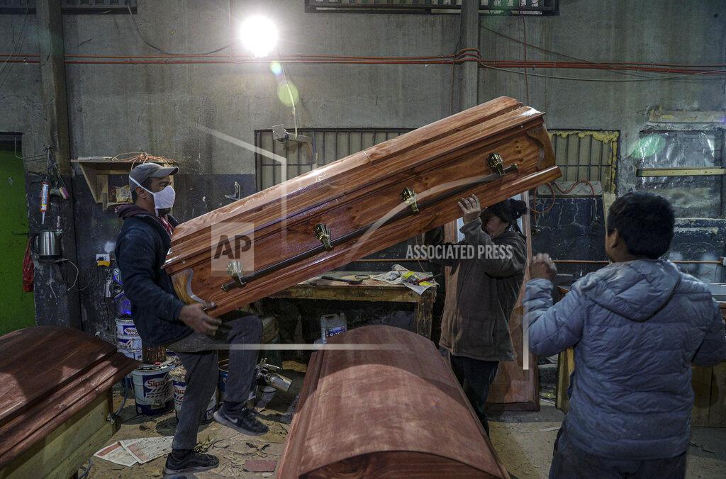 Esteban Felix Coffin makers lift a casket at the Bergut Funeral Services factory in Santiago, Chile, Thursday, June 18, 2020. The coffin production has had to increase up to 120%, according to Nicolas Bergerie, owner of the factory. His more basic coffin model is called the COVID model and is made to cope with the increase of deaths during the coronavirus pandemic. (AP Photo/Esteban Felix)