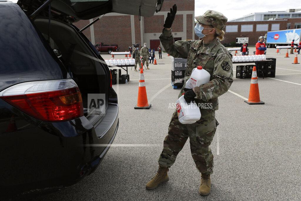 Massachusetts U.S. Army National Guard soldier Colleen Bearce, of Hanover, Mass., places gallon containers of milk in the trunk of a vehicle at an event sponsored in part by Dairy Farmers of America, at Boston College High School, Thursday, May 7, 2020, in Boston. Dairy farmers have a milk surplus because demand has dropped as schools and restaurants closed during the corona virus pandemic, and some farmers have had to pour excess milk away. (AP Photo/Steven Senne)