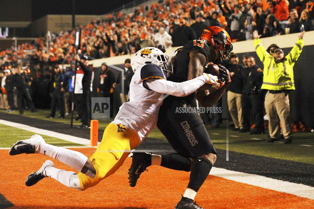 Brody Schmidt Oklahoma State wide receiver Tyron Johnson, right, catches a touchdown pass while under pressure from West Virginia cornerback Josh Norwood during the second half of an NCAA college football game in Stillwater, Okla., Saturday, Nov. 17, 2018. Oklahoma State upset West Virginia 45-41.(AP Photo/Brody Schmidt)