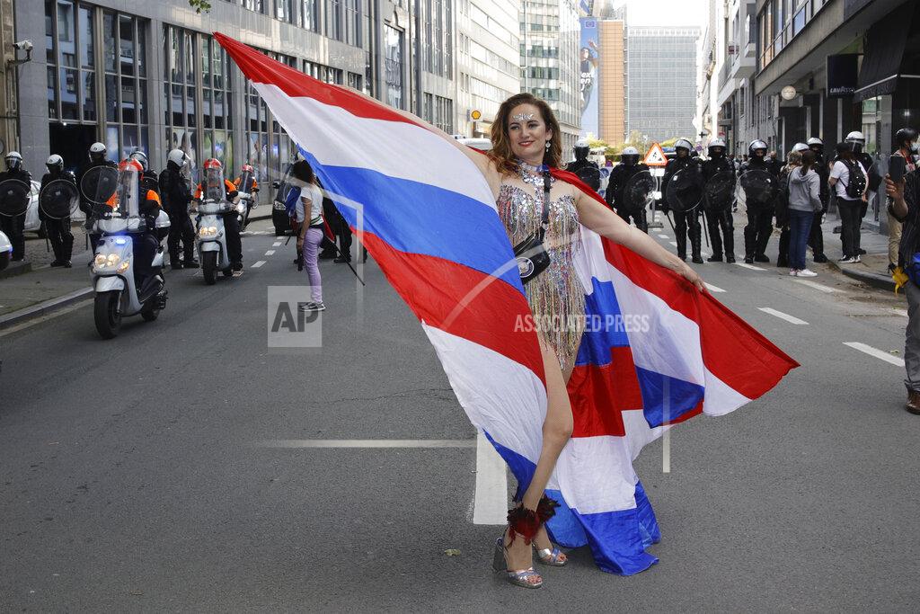 Olivier Matthys A woman dances in front of a police security line as people gather near EU headquarters during a so called "European Demonstration for Freedom and Democracy" protest against COVID-19 security measures taken by European governments, in Brussels, Saturday, May 29, 2021. (AP Photo/Olivier Matthys)