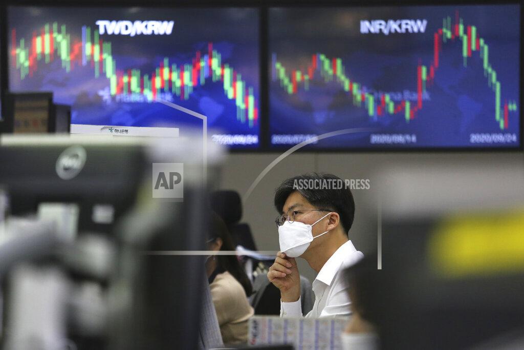 A currency trader adjusts his face mask at the foreign exchange dealing room of the KEB Hana Bank headquarters in Seoul, South Korea, Thursday, Sept. 24, 2020. Asian shares were mostly lower Thursday as caution again after a retreat on Wall Street driven by a decline in technology shares.(AP Photo/Ahn Young-joon)