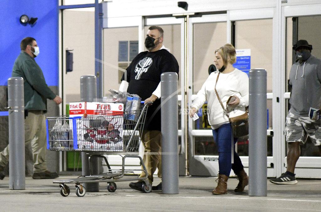 Warren Dillaway Shoppers leave Walmart around 5:30 a.m. on Friday, Nov. 27, 2020, in Ashtabula Township, Ohio. John Kirk, pushing cart, and Diane Simms, second from right, decided to try the Black Friday experience but many shoppers sat out the traditional start to the holiday shopping season. (Warren Dillaway/The Star-Beacon via AP)
