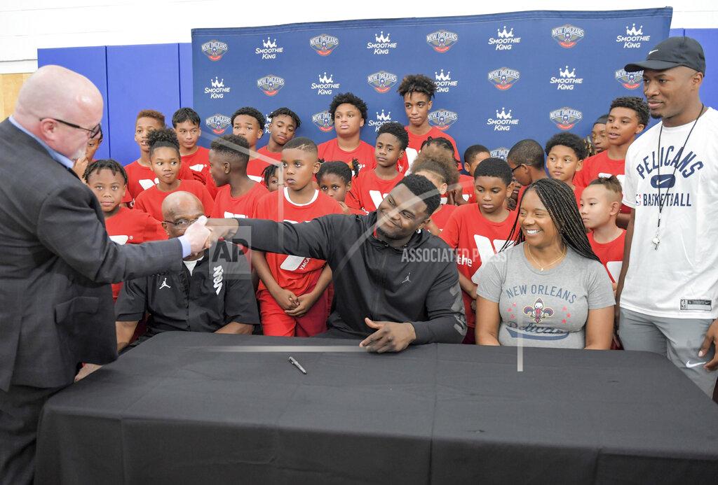 Max Becherer New Orleans Pelicans forward Zion Williamson shakes hands with New Orleans Pelicans vice president of basketball operations David Griffin after signing his contract extension surrounded by his family and children attending camp at the Dryades YMCA in New Orleans, Wednesday, July 6, 2022. (Max Becherer/The Times-Picayune/The New Orleans Advocate via AP)