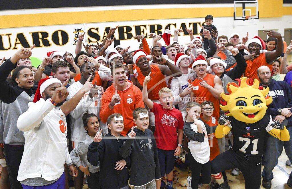 Ken Ruinard Teachers and students from Arizona celebrate with Orange Crushem, the half of the Clemson football team who finished putting together 750 backpacks with supplies before the other half finished, at Saguaro High School in Scottsdale, Ariz., Wednesday, Dec. 25, 2019. Fiesta Bowl Charities, in partnership with an Arizona nonprofit, Back to School Clothing Drive, hosting the friendly supply packing competition providing 1,500 school supply bags for Title I students across the state. (Ken Ruinard/The Independent-Mail via AP)