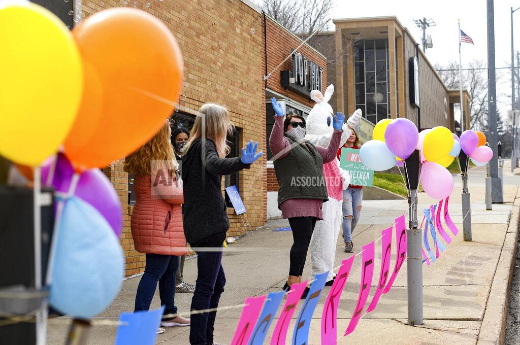 Erin Bormett Volunteers wave at passing cars, encouraging families to meet the Easter Bunny from their vehicles on Saturday, April 11, 2020 on the curb of New Life Church in downtown Sioux Falls, S.D. Churches around the city are finding social distancing-safe methods of celebrating Easter during the coronavirus pandemic. (Erin Bormett/The Argus Leader via AP)