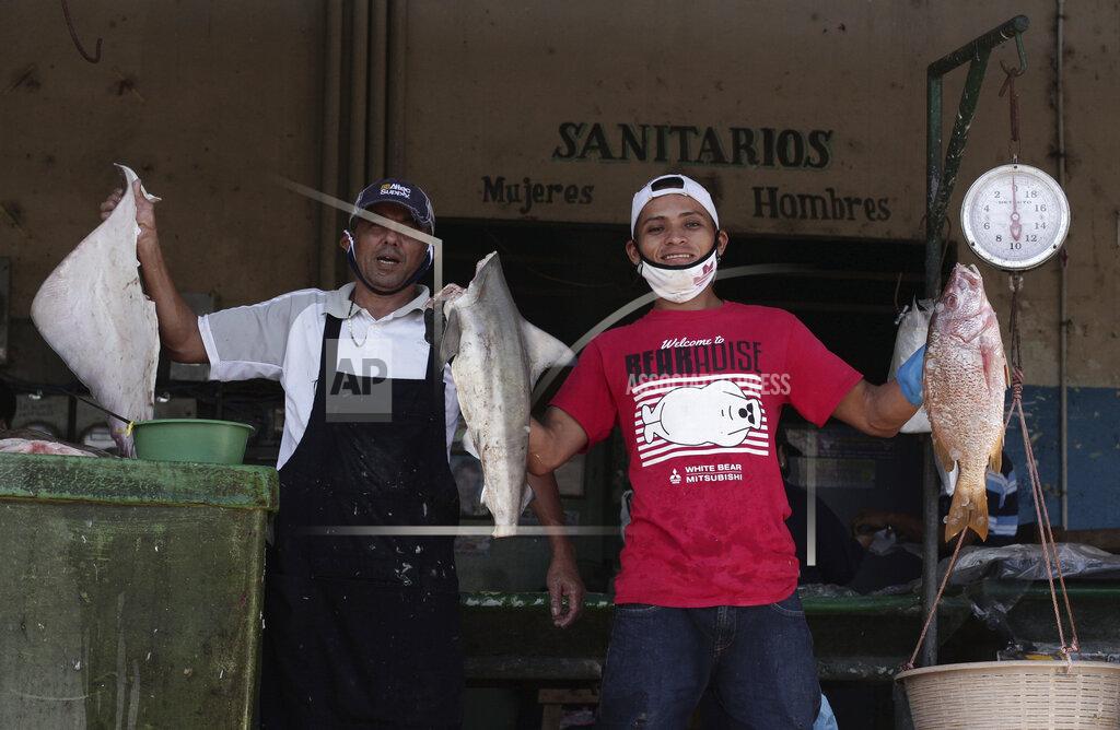 Seafood vendors show off their products at La Tiendona Market on their second day back to work, three-months after a lockdown aimed at preventing the spread of the new coronavirus in San Salvador, El Salvador, Tuesday, June 16, 2020. The Legislative Assembly passed legislation early Friday that would extend a state of emergency in the country for another two weeks, but eliminate the nearly universal mandatory stay-at-home order except for those who tested positive for COVID-19 and those returning from abroad. (AP Photo/Salvador Melendez)