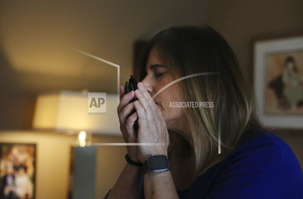 Michelle Pepe tries to smell her late father's wallet while going through his belongings one year after he died of the coronavirus, in Sharon, Mass., on Wednesday, April 14, 2021. After contracting the virus herself, Pepe lost and has not regained her sense of smell. She keeps her father's belongings in hopes that one day it comes back and she can smell him again. (AP Photo/Jessie Wardarski)