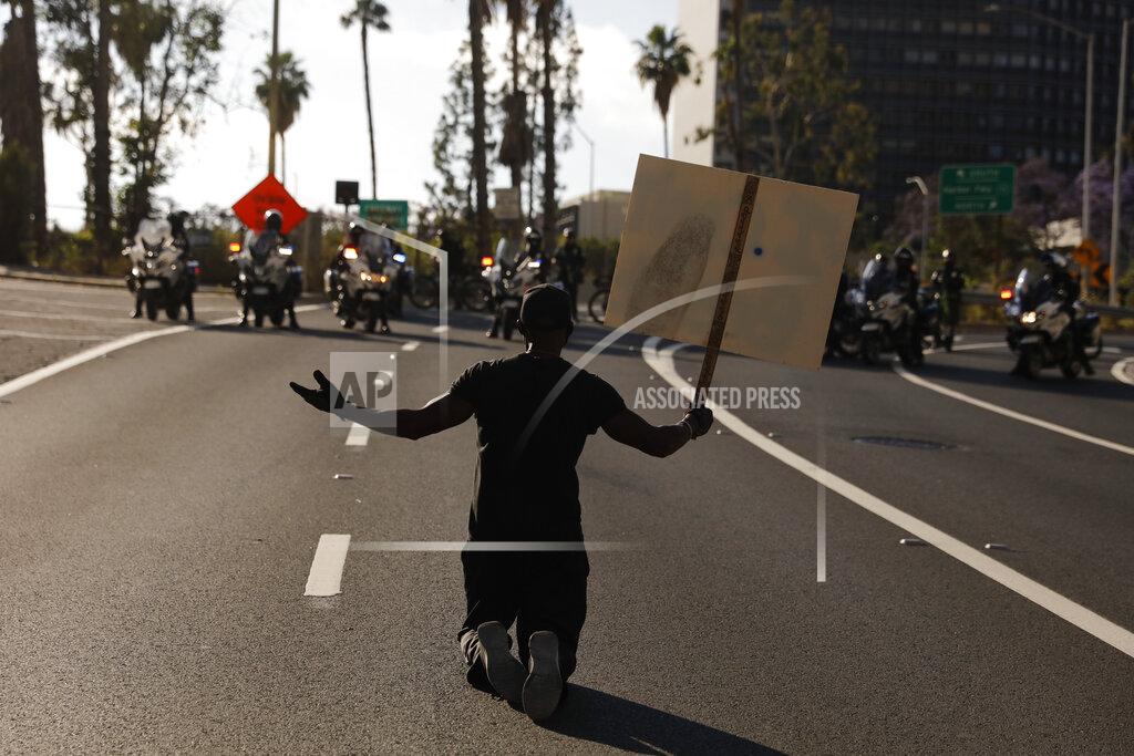 Jae C. Hong A man kneels on the street in front of police officers while chanting "I can't breathe" during a protest over the death of George Floyd, Friday, May 29, 2020, in Los Angeles. Floyd died Memorial Day while in police custody in Minneapolis. (AP Photo/Jae C. Hong)
