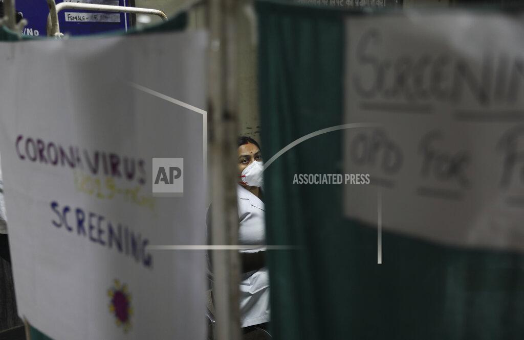 In this Thursday, March 12, 2020, photo, a doctor screens a patient at a homeopathic college and hospital in New Delhi, India. With no approved drugs for COVID-19, some people are turning to alternative medicines, often with governments promoting them. (AP Photo/Manish Swarup)