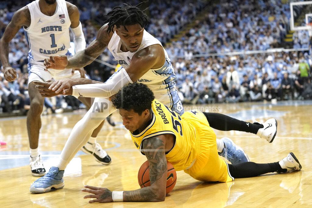 Gerry Broome North Carolina guard Caleb Love, top, and Michigan guard Eli Brooks (55) chase the ball during the second half of an NCAA college basketball game in Chapel Hill, N.C., Wednesday, Dec. 1, 2021. (AP Photo/Gerry Broome)