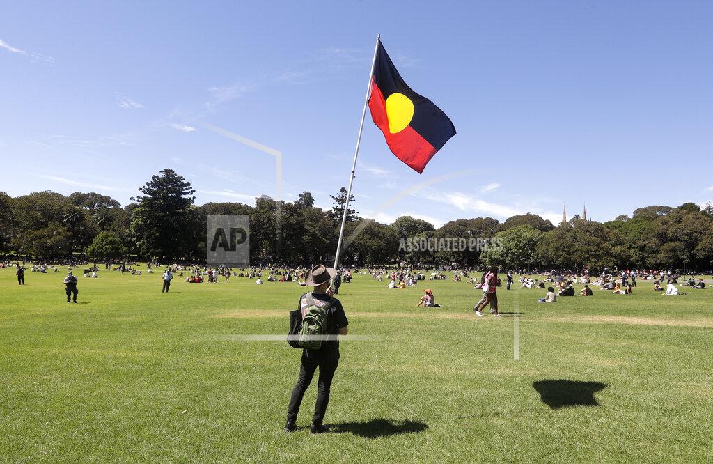 Rick Rycroft A man holds an Aboriginal flag in a social distanced crowd during an Aboriginal-lead Invasion Day rally on Australia Day in Sydney, Tuesday, Jan. 26, 2021. Many of Australia's First Nations people say that sovereignty has never been ceded and oppose ongoing colonial violence and destruction. (AP Photo/Rick Rycroft)