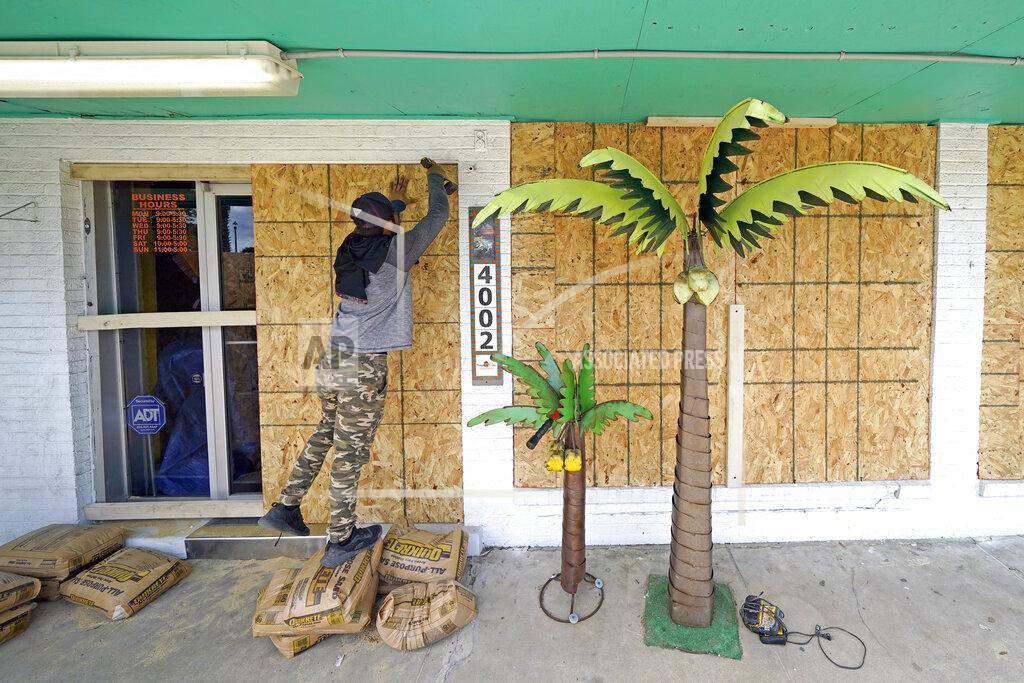 David J. Phillip Issac Alvarado boards up windows of coastal decor store Bayside Chic, Tuesday, Aug. 25, 2020, in Galveston, Texas, as Hurricane Laura heads toward the Gulf Coast. (AP Photo/David J. Phillip)