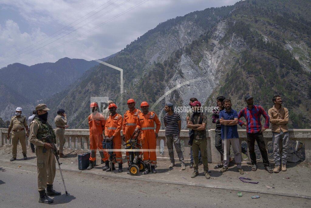 Dar Yasin National Disaster Response Force (NDRF) members and villagers watch from a distance as earth movers dig through rubble of a collapsed tunnel in Ramban district, south of Srinagar, Indian controlled Kashmir, Friday, May 20, 2022. An official in Indian-controlled Kashmir said Friday that 10 workers were trapped after part of a road tunnel collapsed in the Himalayan region. (AP Photo/Dar Yasin)