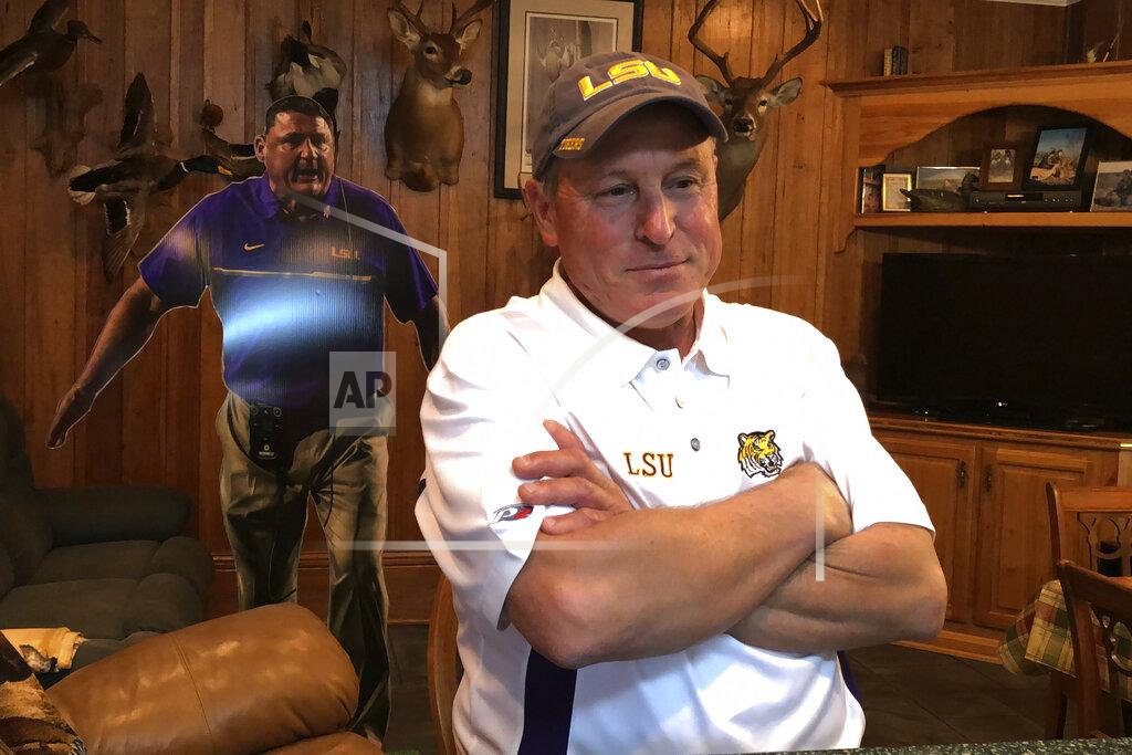 Brett Martel Don “Noochie” Adams stands in front of a cardboard cutout of childhood friend Ed Orgeron, the NCAA college football coach at LSU, in his home in Cut Off, La., Thursday, Jan. 9, 2020. Cajun pride is swelling in Lafourche Parish now that the former two-way football standout who won a 1977 state title for the South Lafourche High School Tarpons is on the brink of capping off arguably the LSU Tigers' greatest season in the program's 126-year history with a national title. No. 1 LSU plays third-ranked Clemson on Monday night in the College Football Playoff championship in New Orleans, about 60 miles northeast of where Orgeron grew up. (AP Photo/Brett Martel)