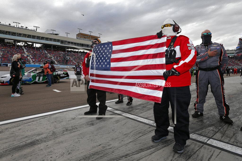 Ralph Freso Fire and Safety crew members hold a United States flag on pit road prior to an NASCAR Xfinity Series auto race at Phoenix Raceway, Saturday, Nov. 7, 2020, in Avondale, Ariz. (AP Photo/Ralph Freso)