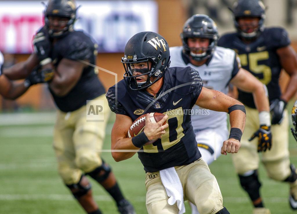 Nell Redmond FILE - In this Saturday, Sept. 8, 2018, file photo, Wake Forest quarterback Sam Hartman carries the ball against Towson in the second half of an NCAA college football game in Winston-Salem, N.C. Hartman won the job in camp after presumptive starter Kendall Hinton was suspended for three games for violating team rules. The former backup is second in the ACC with 278 passing yards per game to go with six touchdowns and five interceptions (AP Photo/Nell Redmond, File)