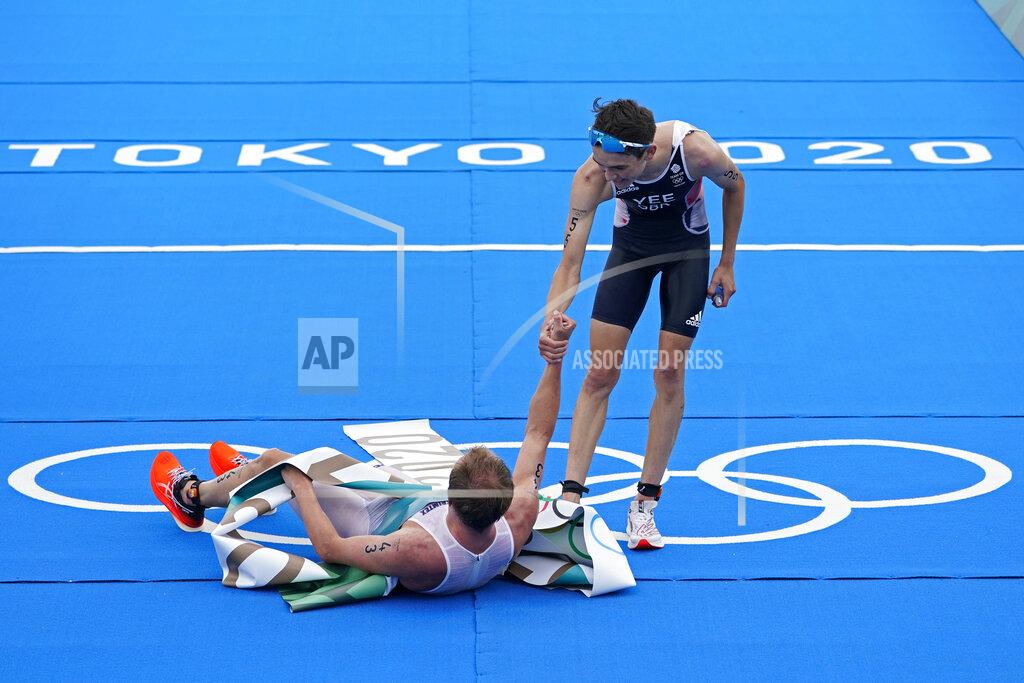 David Goldman Alex Yee of Great Britain (55) reaches to help up Kristian Blummenfelt of Team Norway (43) after Blummenfelt won the gold medal and Yee won silver during the men's individual triathlon at the 2020 Summer Olympics, Monday, July 26, 2021, in Tokyo, Japan. (AP Photo/David Goldman)