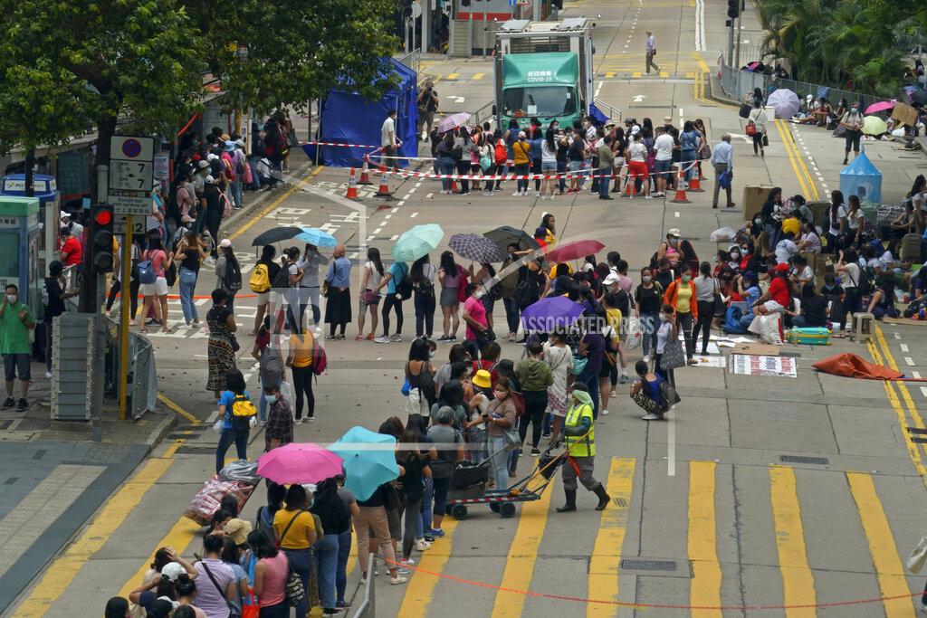 Kin Cheung In this Saturday, May 1, 2021, photo, domestic helpers from the Philippines line up at the temporary testing center for COVID-19, in Hong Kong. Hong Kong officials have dropped a plan to make it mandatory for foreign domestic workers to be vaccinated against the coronavirus, after the move drew criticism that it was discriminatory. (AP Photo/Kin Cheung)