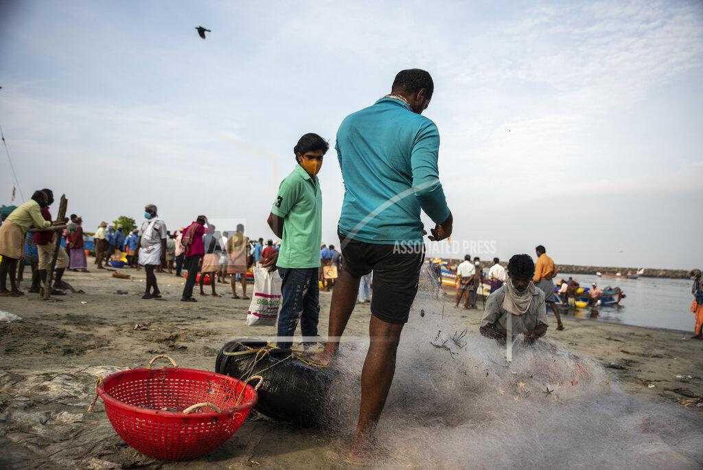 R S Iyer A man wearing a mask as a precaution against COVID-19 watches fishermen clear their nets on the Arabian Sea coast in Kochi, Kerala state, India, Monday, Sept.20, 2021. The tiny southern state continues to battle the highest number of coronavirus cases in the country. (AP Photo/R S Iyer)