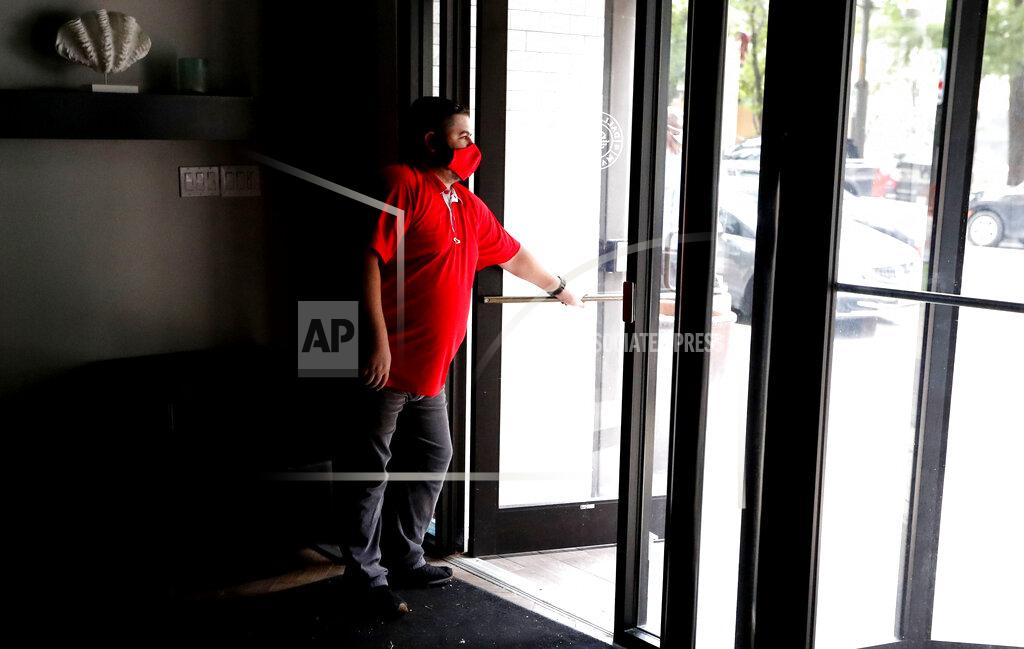 Lm Otero Wearing a mask amid concerns of the spread of the coronavirus, Dimitris Anagnostis opens the door to Chop House Burgers before the restaurant opened in downtown Dallas, Wednesday, July 8, 2020. (AP Photo/LM Otero)