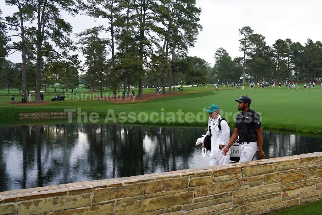 Tony Finau walks across the Sarazen Bridge with his caddie Mark Urbanek on the 15th hole during the third round of the Masters golf tournament on Saturday, April 10, 2021, in Augusta, Ga. (AP Photo/Matt Slocum)