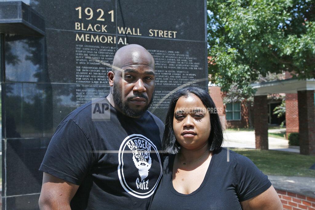 Sue Ogrocki Shawn-Du Stackhouse, left, and Chelsea Guillory, right, pose for a photo at the Black Wall Street Memorial in Tulsa, Okla., Monday, June 15, 2020. For Stackhouse, a barber from the Washington, D.C. area and one of those visiting the Tulsa massacre memorials on this day, the proof that cell-phone videos provided of killings of African-Americans today somehow make the killings of the past, like Tulsa's, more real as well. (AP Photo/Sue Ogrocki)