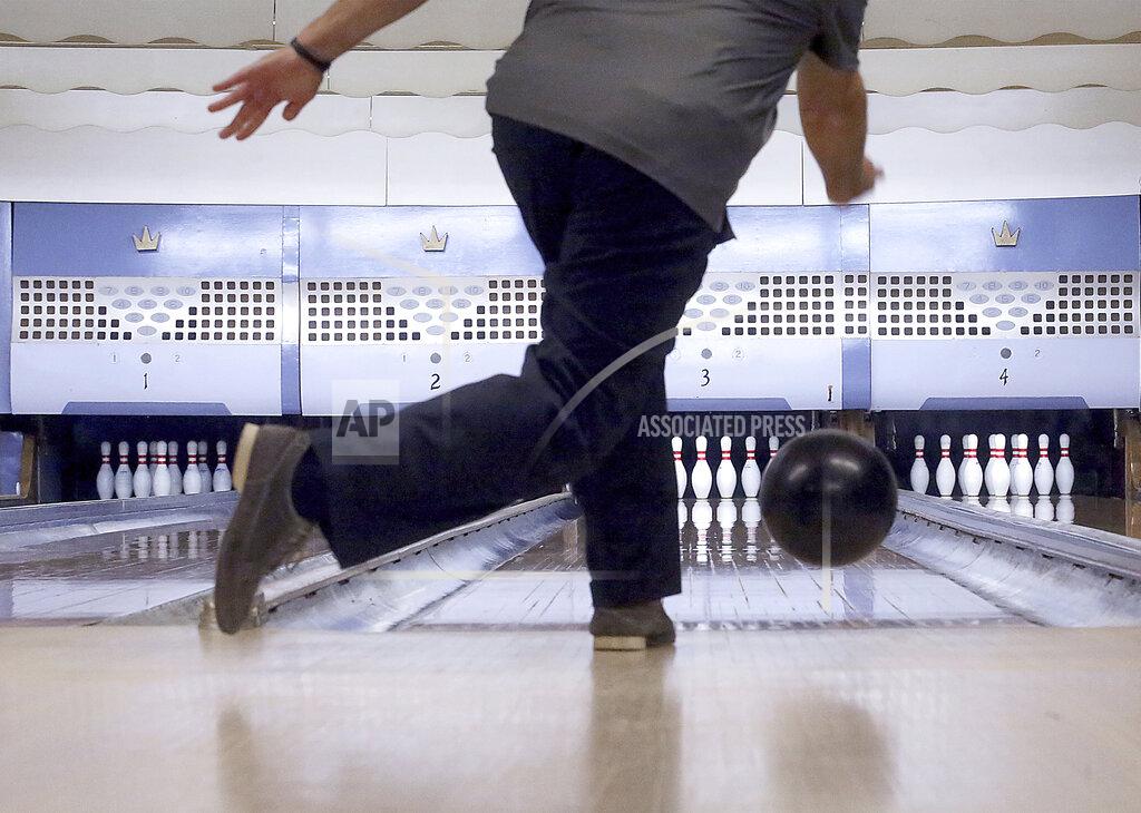 John Hart FILE - In this Oct. 29, 2017, file photo, Chris Head, of Milwaukee, Wis., delivers a ball down one of the alley's four lanes during a visit to Strikes, Spares & Spirits in Iron Ridge, Wis. Like many industries in America and around the world, bowling has taken a huge financial blow because of lockdown measures meant to contain the highly contagious virus. (John Hart/Wisconsin State Journal via AP, File