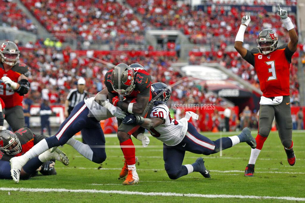 Tampa Bay Buccaneers running back Ronald Jones II (27) slips between Houston Texans inside linebacker Zach Cunningham (41) and linebacker Tyrell Adams (50) for a score during the first half of an NFL football game Saturday, Dec. 21, 2019, in Tampa, Fla. Quarterback Jameis Winston (3) celebrates the play. (AP Photo/Mark LoMoglio)