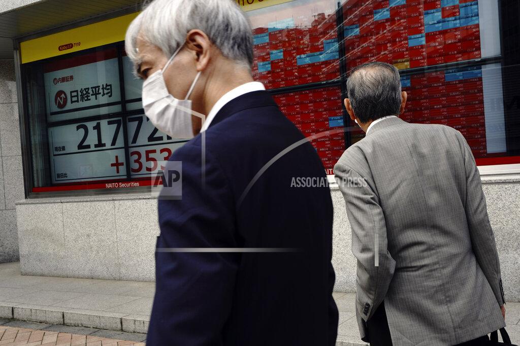 A man wears a mask in front of an electronic stock board showing Japan's Nikkei 225 index at a securities firm in Tokyo Thursday, May 28, 2020. Asian stocks are mixed after an upbeat open, as hopes for an economic rebound from the coronavirus crisis were dimmed by tensions between the U.S. and China over Hong Kong and other issues. (AP Photo/Eugene Hoshiko)