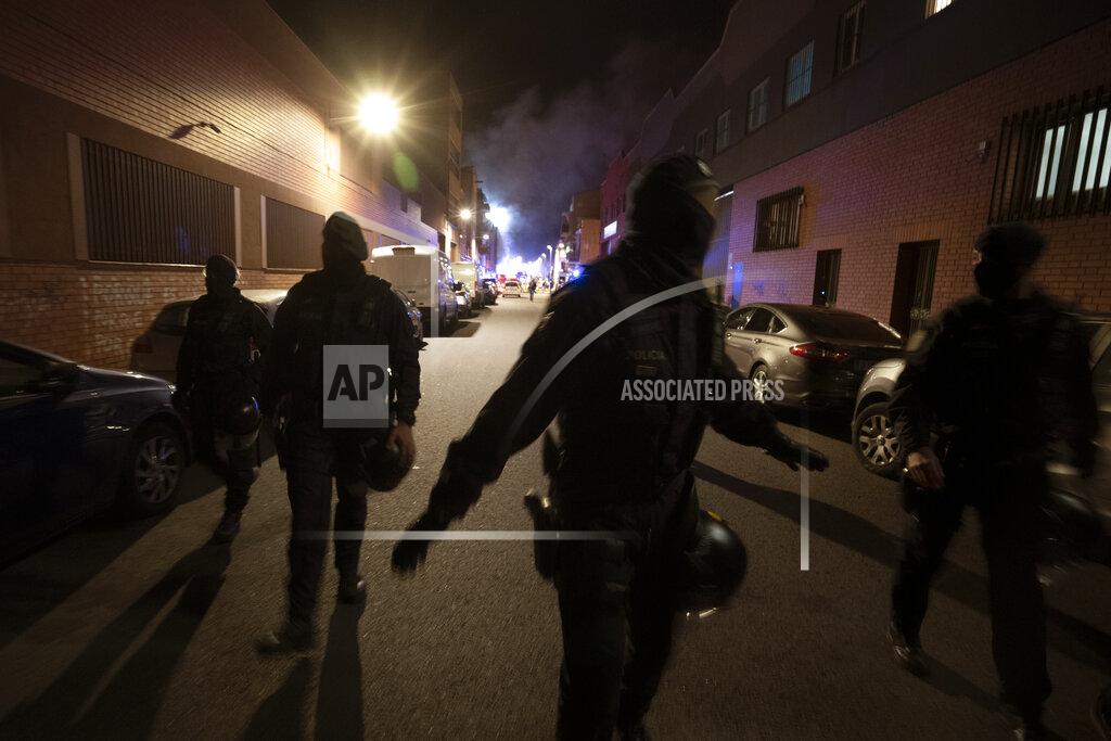 Joan Mateu Police officers cordon off the street as firefighters work to extinguish a fire at a building in Badalona, Barcelona, Spain, Thursday, Dec. 10, 2020. Authorities in northeastern Spain say a fire has raged through an abandoned building occupied by squatters in the city of Badalona, injuring at least 17 people, including two in critical condition. Firefighters say they rescued around 30 people from windows as the building burned late Wednesday. (AP Photo/Joan Mateu)