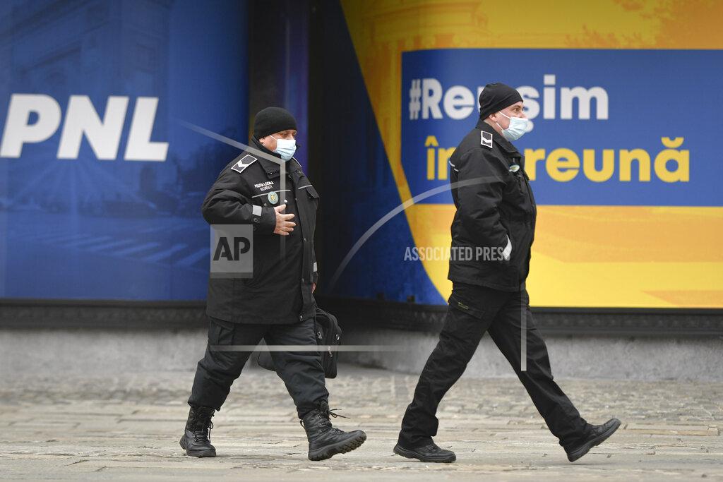 Andreea Alexandru Police officers wearing masks for protection against the COVID-19 infection walks by the logo of the Liberal Party in Bucharest, Romania, Thursday, Dec. 3, 2020. Romania will hold parliamentary elections on Sunday Dec. 6. Text reads "We will succeed together". (AP Photo/Andreea Alexandru)