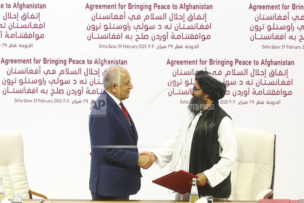 FILE - In this Feb. 29, 2020 file photo, U.S. peace envoy Zalmay Khalilzad, left, and Mullah Abdul Ghani Baradar, the Taliban group's top political leader shake hands after signing a peace agreement between Taliban and U.S. officials in Doha, Qatar. An Afghan official said Thursday, May 14, 2020, that a suicide attack in eastern Afghanistan targeted a military compound but was detonated before it reached the compound killing several civilians and wounding tens of others. The Taliban took responsibility for the bombing calling it retaliation for statements Tuesday by President Ashraf Ghani blaming Taliban for a brutal attack on a maternity hospital that killed tens of people, an attack that the Taliban were quick to condemn. (AP Photo/Hussein Sayed, File)