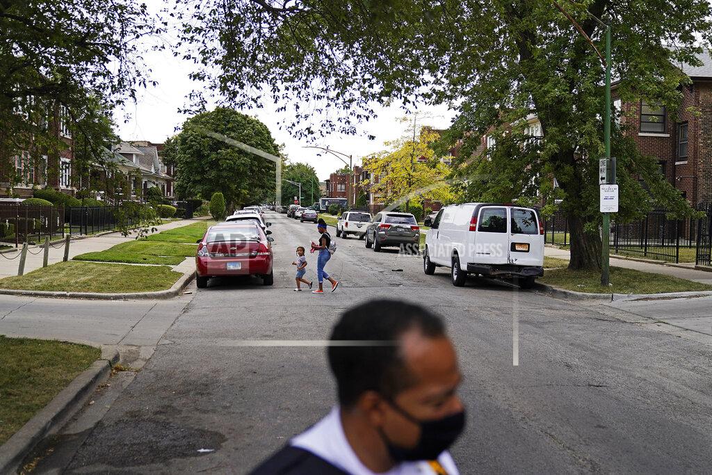 David Goldman A woman and child cross a street as Police Commander Rahman Muhammad patrols though the Auburn Gresham neighborhood in Chicago, Tuesday, Aug. 25, 2020. Muhammad says solving crimes has become tougher because of "an erosion of trust between the police and the community." Residents fear their own safety, and so are less inclined to cooperate. Attitudes have changed, too. Years ago, "we would be able to go to a leader of a gang and have a conversation ... and have some type of mutual respect or rapport," Muhammad says. "That's different now." (AP Photo/David Goldman)